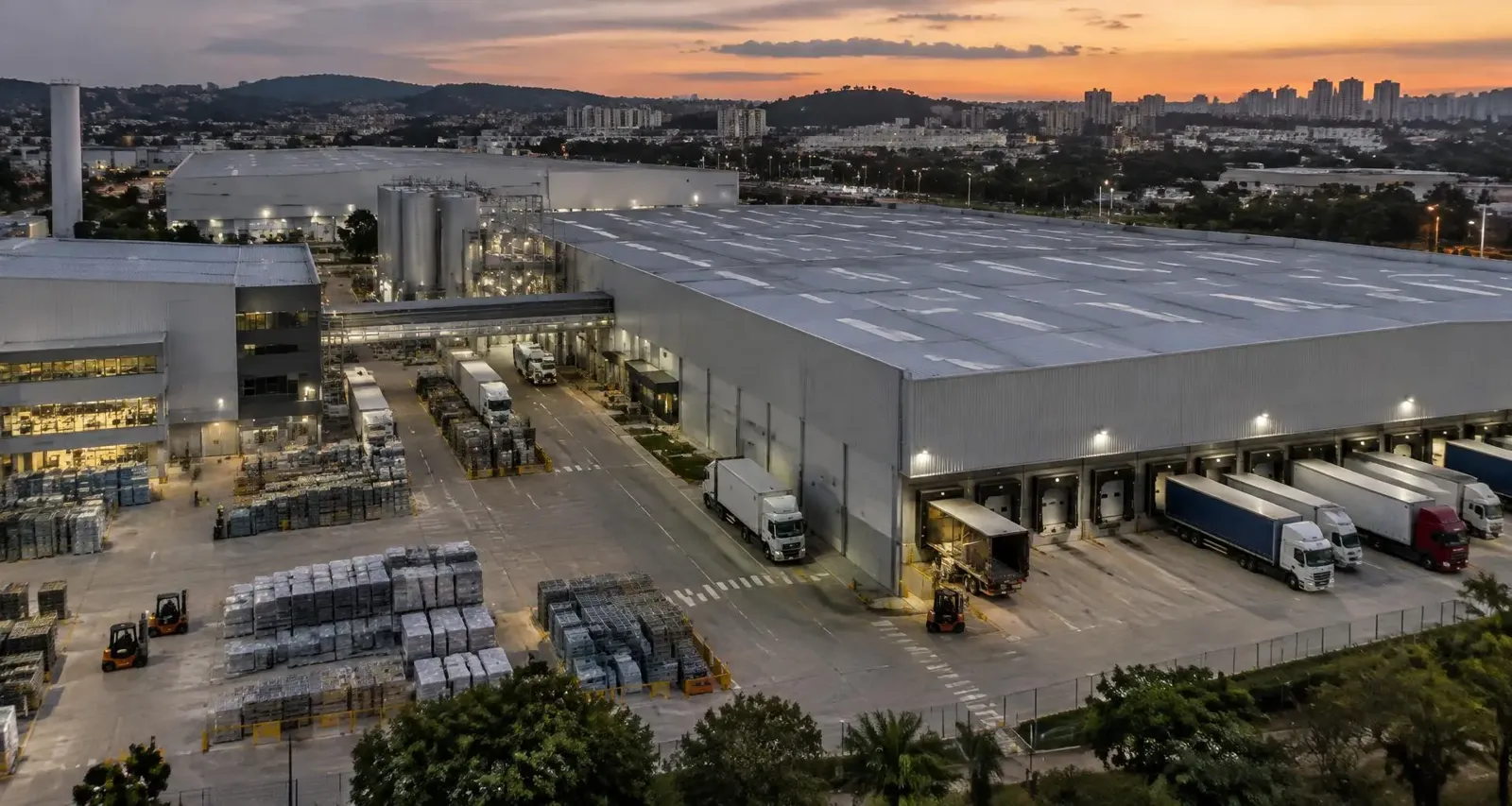 Imagem ilustrativa gerada por IA: complexo industrial e logístico ao entardecer
