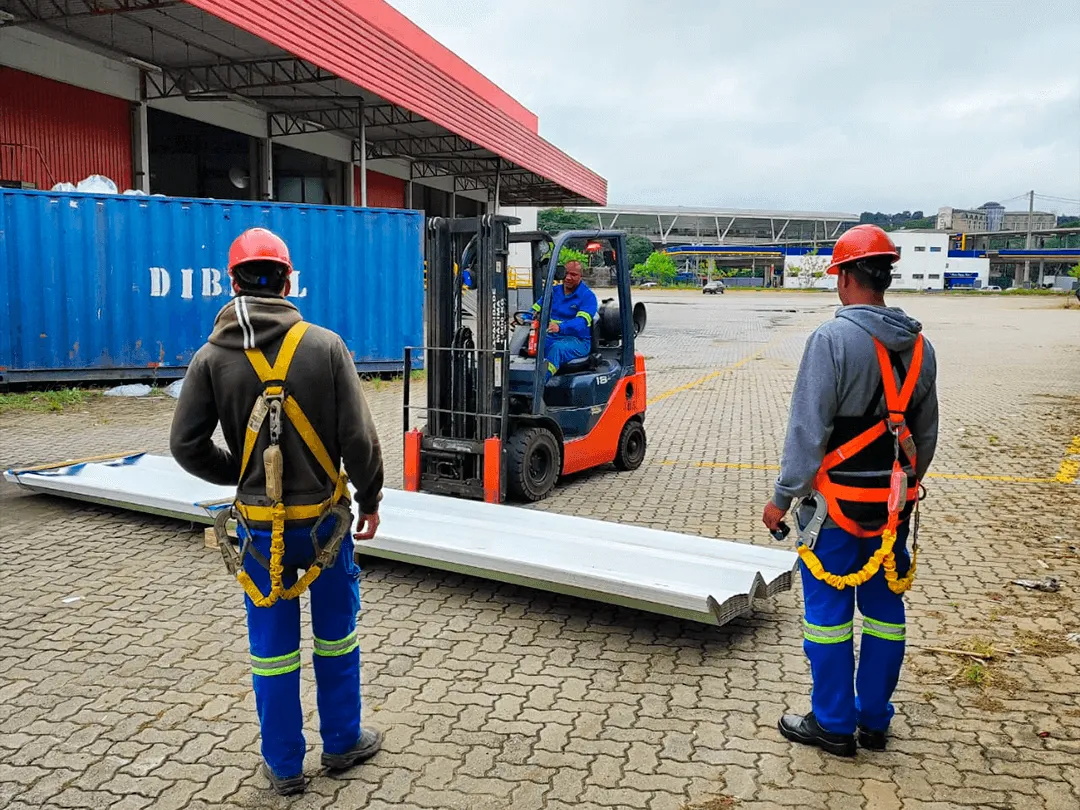 Profissionais com capacete e cinto de segurança em pátio industrial, registro do projeto LAR Segurança do Trabalho